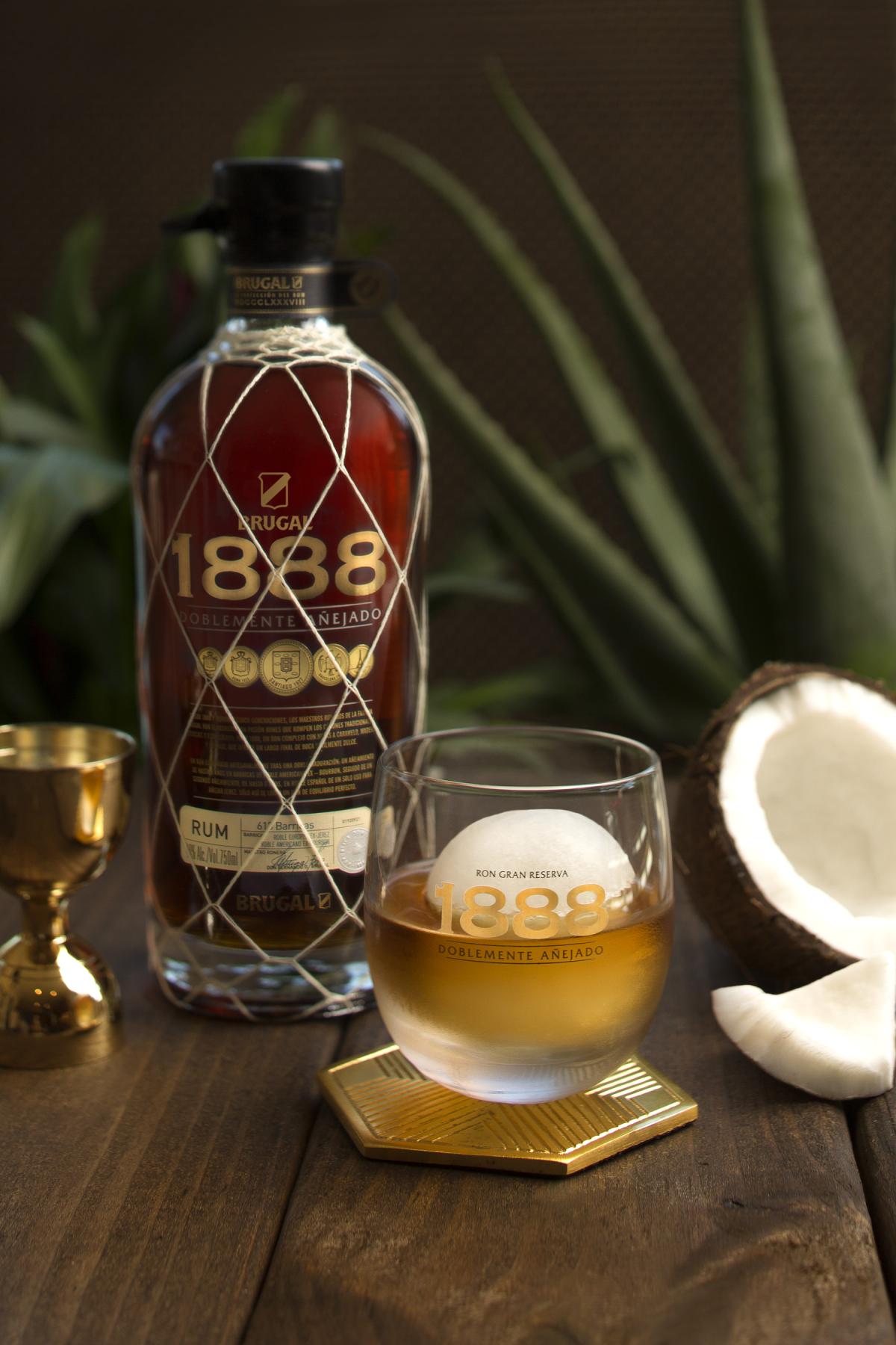 A photo of a bottle of Brugal rum and a glass of rum with an ice ball