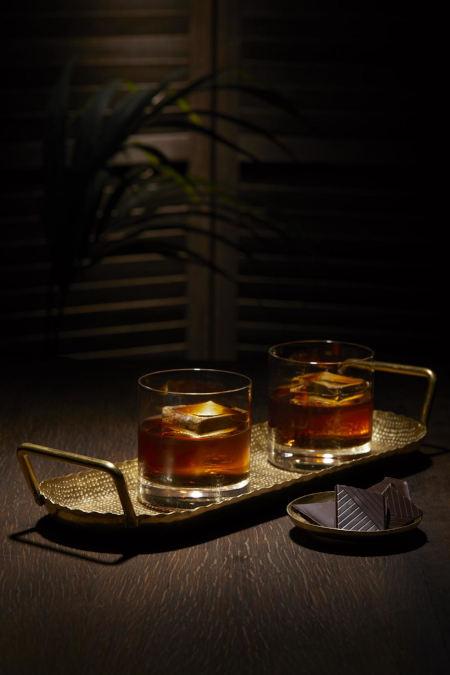 Two Nightcap Rum Old Fashioned Cocktails on a tray beside chocolate